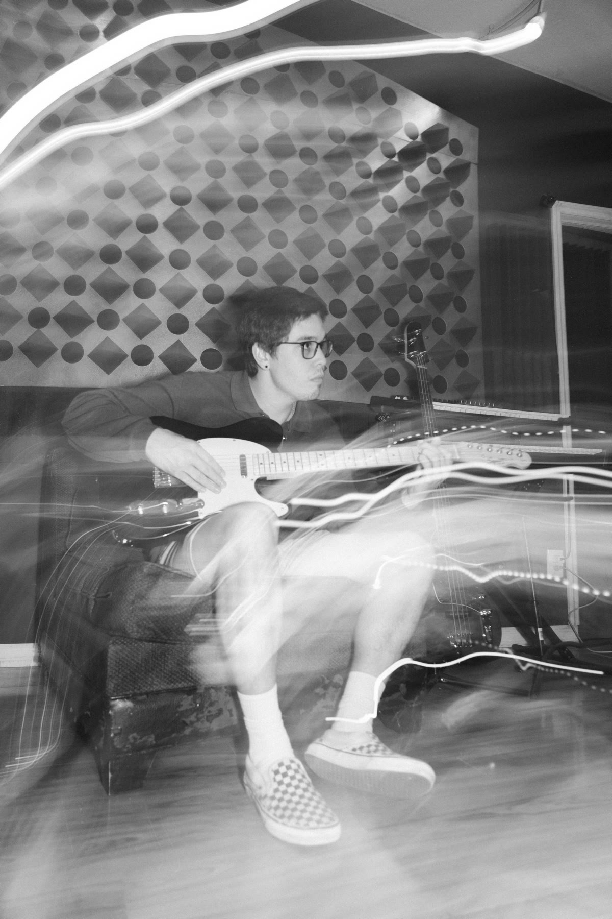 Black and white photo of Nate Sanway playing electric guitar in the studio with light trails